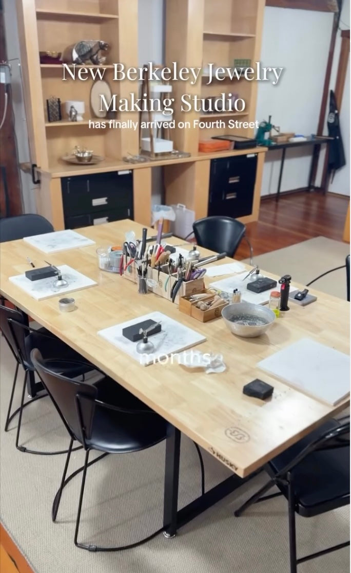 Jewelry making studio with workstations and tools on a wooden table.