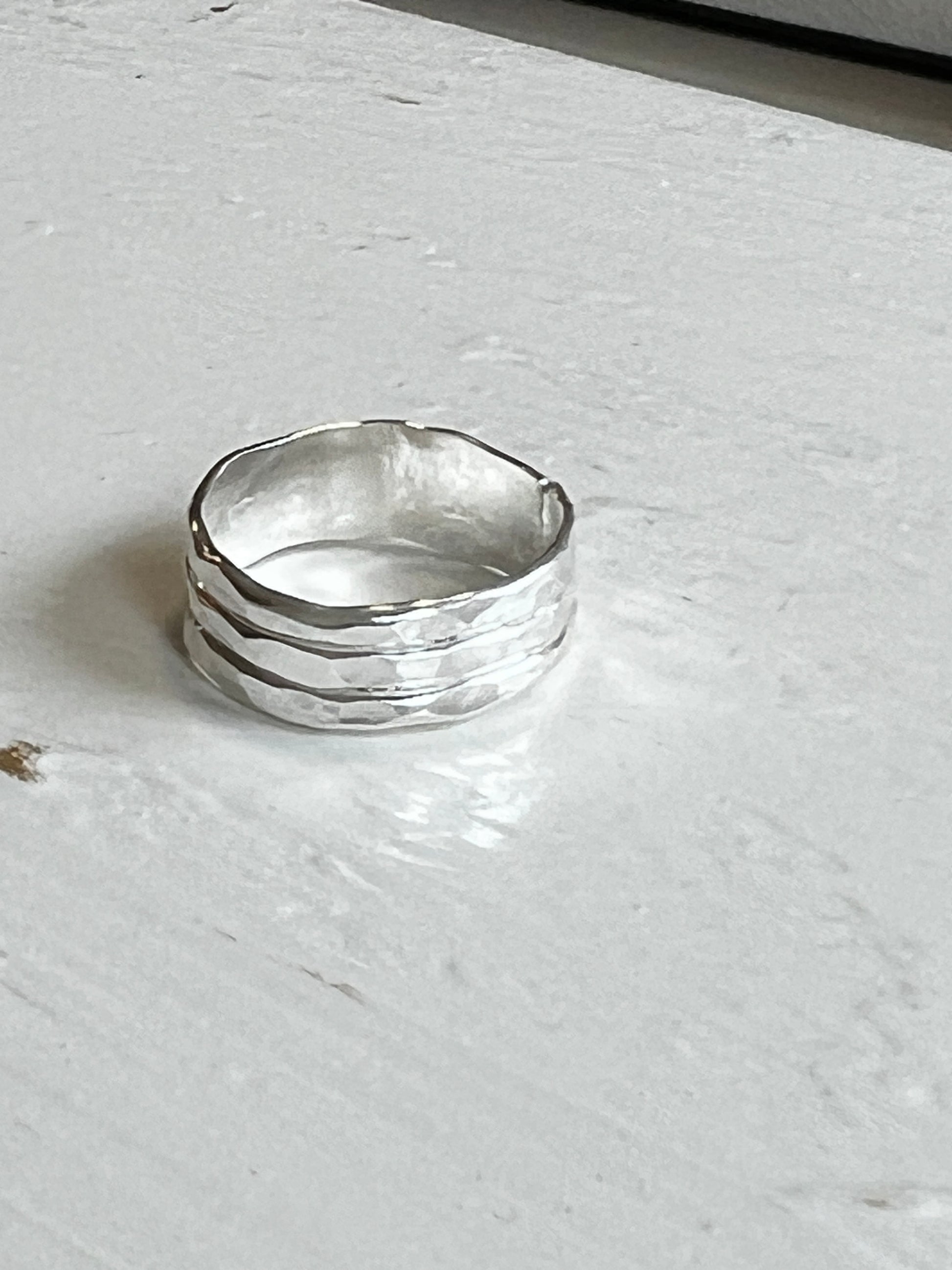 Thick hammered silver ring on a light gray surface